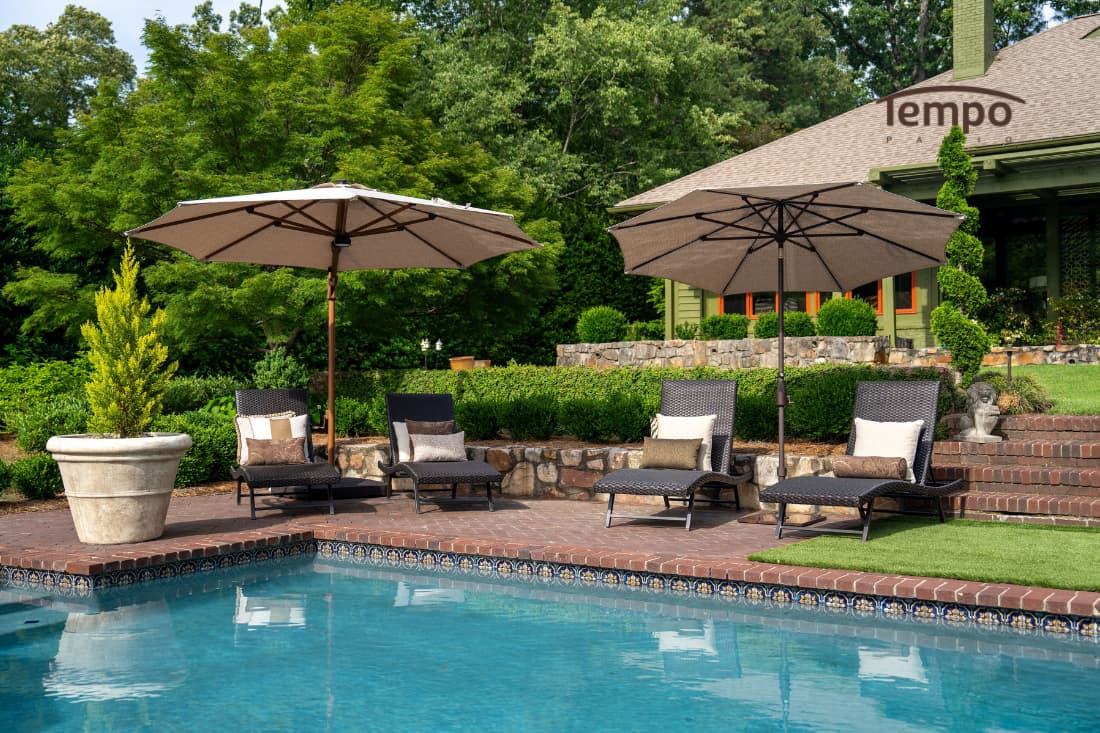 Patio Umbrellas vs Other Shade Options displayed as two beige umbrellas shading wicker loungers beside a backyard pool.