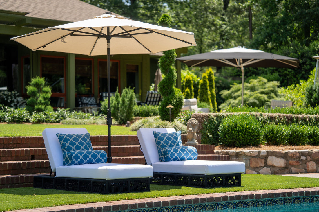 Backyard lounge chairs beside a pool under a large patio umbrella, showing outdoor umbrella basics explained simply for comfortable shaded relaxation.