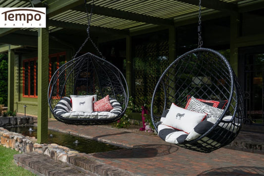 Pros and cons patio umbrellas vs gazebos contrasted by hanging wicker chairs sheltered under a pergola.